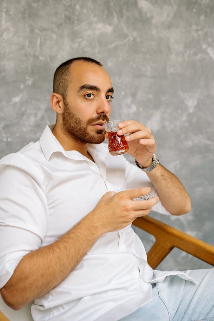Casual portrait of a man with a shaved head drinking tea and relaxing indoors.
