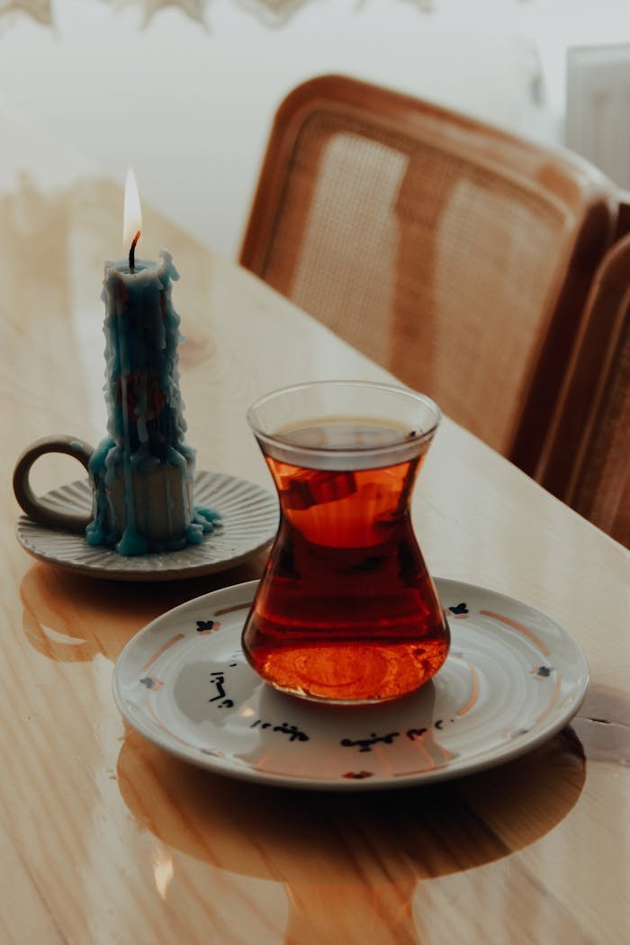 A warm, cozy setting featuring Turkish tea and a lit candle on a wooden table.