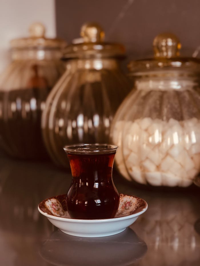 Turkish tea in a traditional glass with sugar jars in the background.